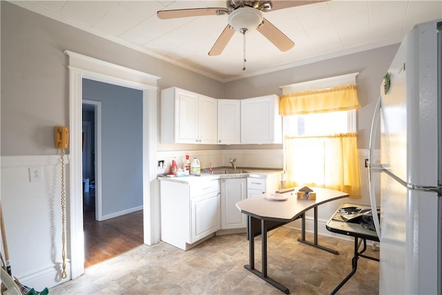 kitchen featuring white refrigerator, white cabinetry, ornamental molding, and sink