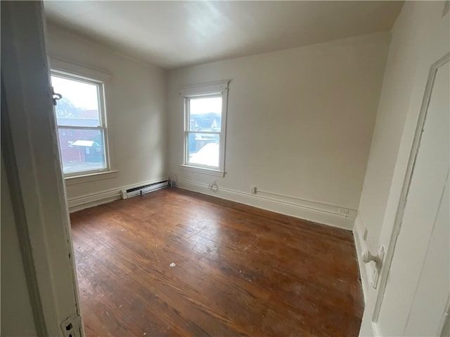 unfurnished room with a baseboard heating unit and dark hardwood / wood-style floors