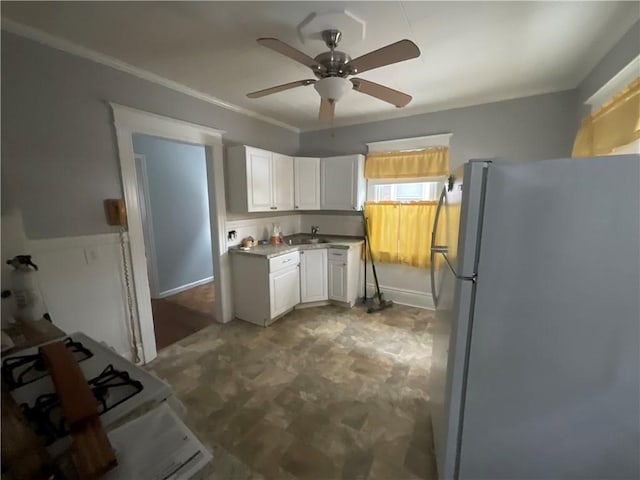 kitchen featuring sink, white cabinets, ceiling fan, crown molding, and white appliances