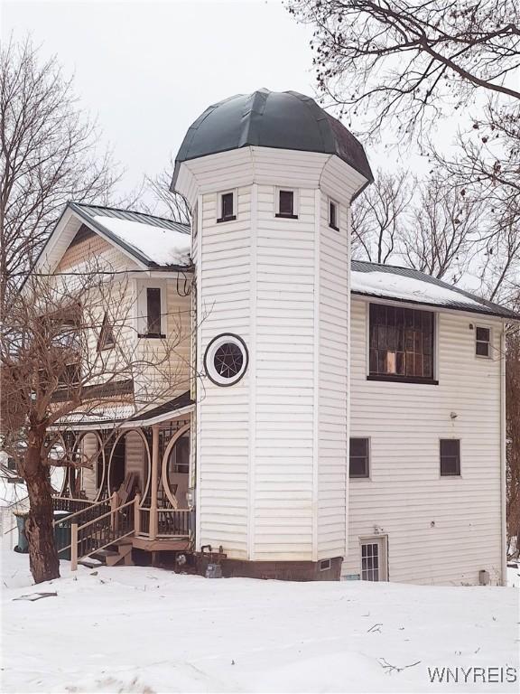 snow covered back of property featuring a porch