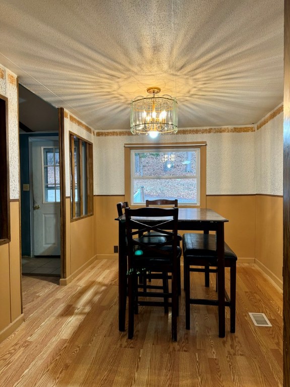 dining area featuring hardwood / wood-style flooring, a chandelier, and a textured ceiling