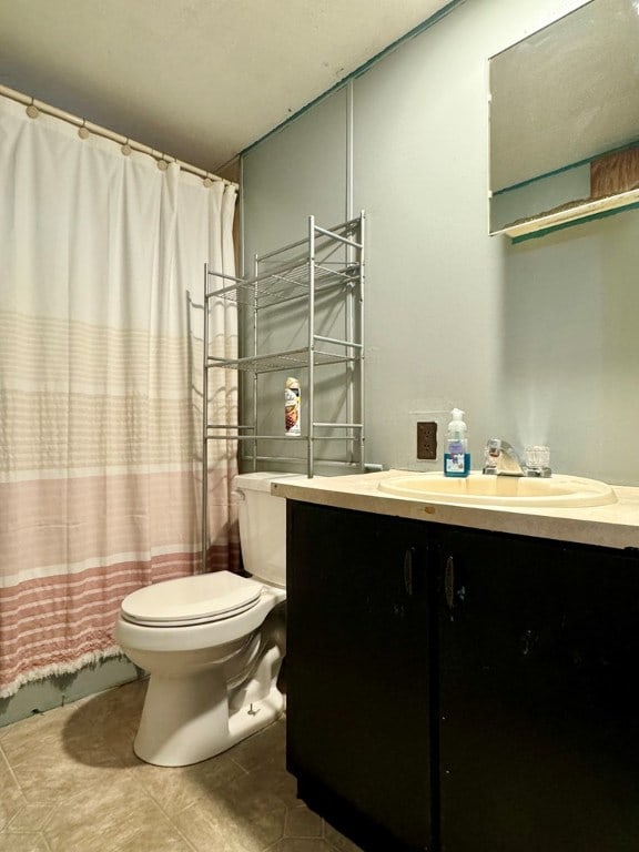 bathroom featuring tile patterned flooring, vanity, walk in shower, and toilet