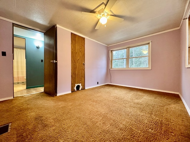 interior space featuring ceiling fan, ornamental molding, a textured ceiling, and carpet