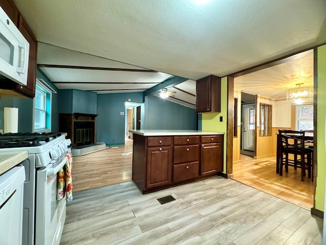 kitchen with dark brown cabinetry, light hardwood / wood-style floors, white appliances, and kitchen peninsula