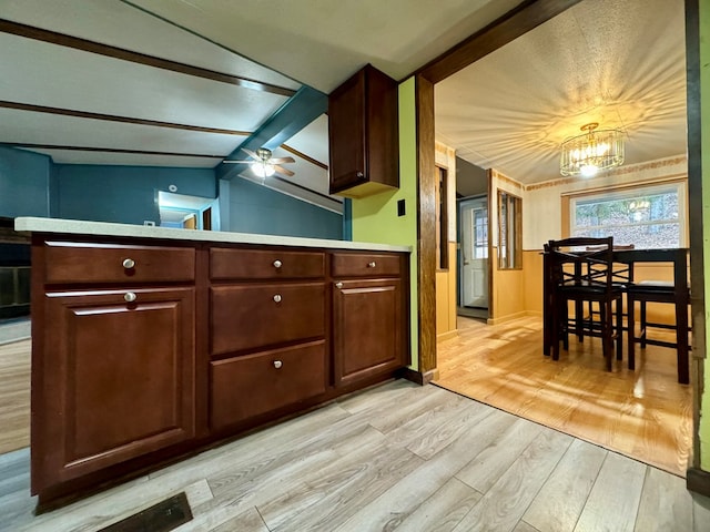 kitchen with vaulted ceiling with beams, dark brown cabinetry, kitchen peninsula, and light wood-type flooring