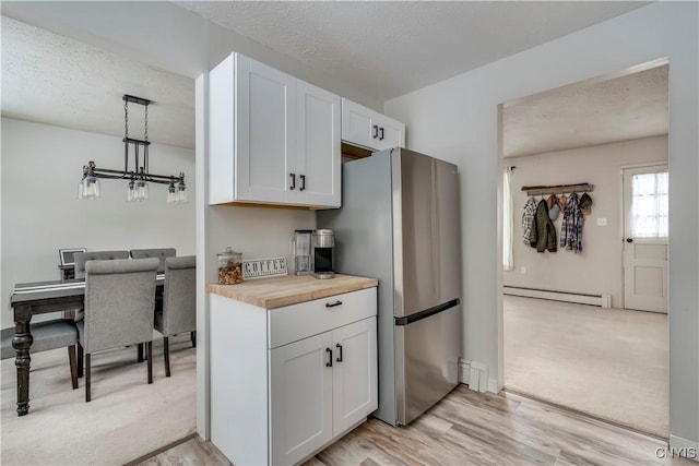 kitchen with wooden counters, pendant lighting, white cabinets, and a baseboard radiator