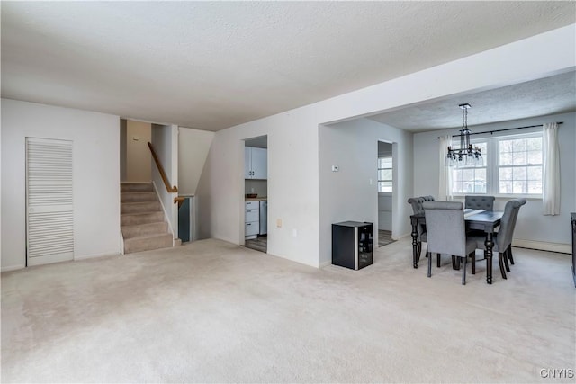 carpeted dining room featuring a baseboard heating unit, a textured ceiling, and a notable chandelier