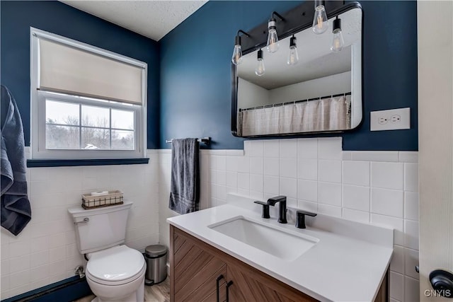 bathroom with vanity, tile walls, and toilet