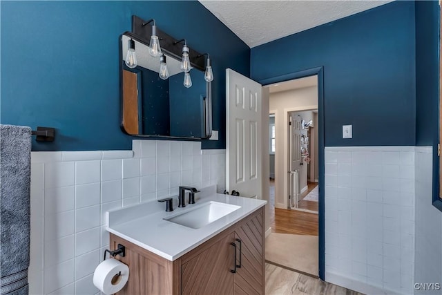 bathroom featuring vanity, a textured ceiling, and tile walls