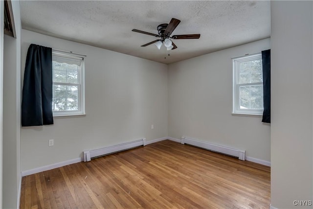 unfurnished room with a baseboard radiator, a healthy amount of sunlight, and light wood-type flooring