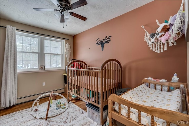 bedroom featuring ceiling fan, wood-type flooring, a textured ceiling, and baseboard heating