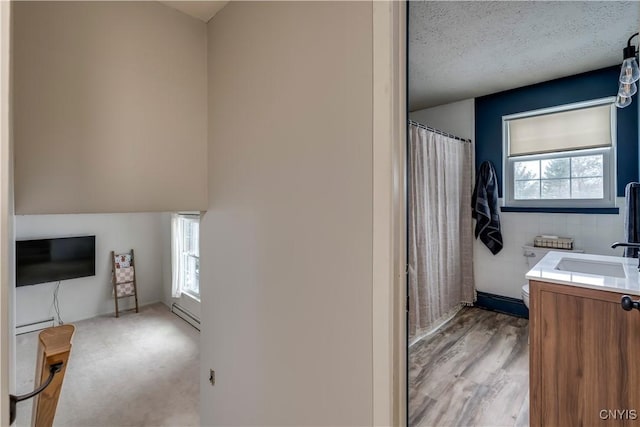 bathroom with baseboard heating, tile walls, vanity, a textured ceiling, and toilet