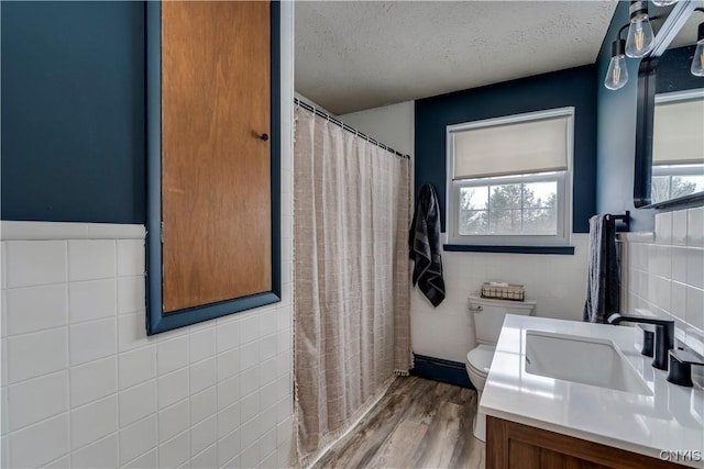 bathroom featuring a healthy amount of sunlight, vanity, tile walls, and a textured ceiling