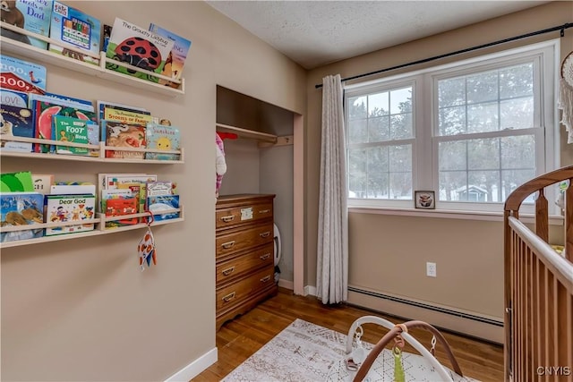 bedroom with dark wood-type flooring, a baseboard radiator, a closet, and a textured ceiling