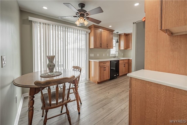 kitchen featuring black dishwasher, sink, hanging light fixtures, ceiling fan, and light hardwood / wood-style floors