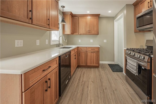 kitchen featuring sink, decorative light fixtures, light hardwood / wood-style flooring, and stainless steel appliances