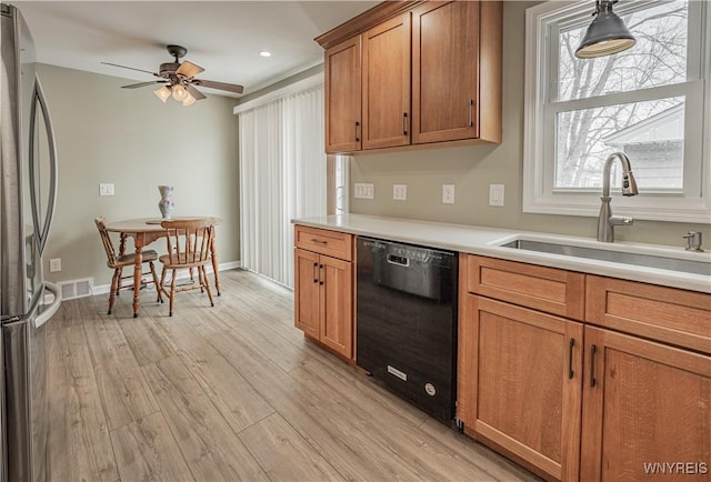 kitchen featuring black dishwasher, sink, stainless steel fridge, ceiling fan, and light hardwood / wood-style flooring