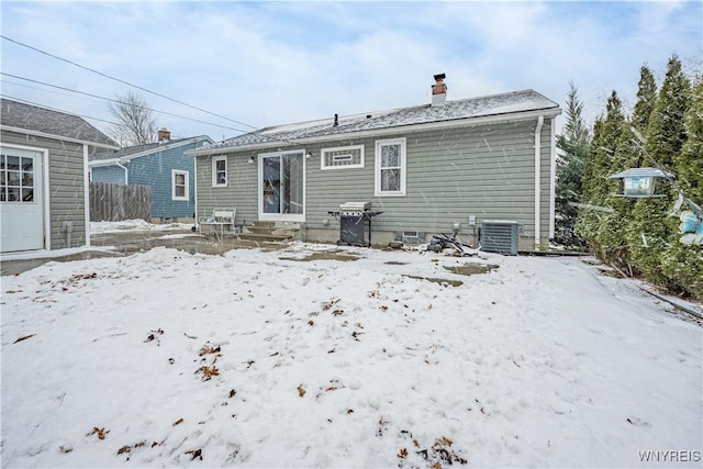 snow covered back of property featuring central AC