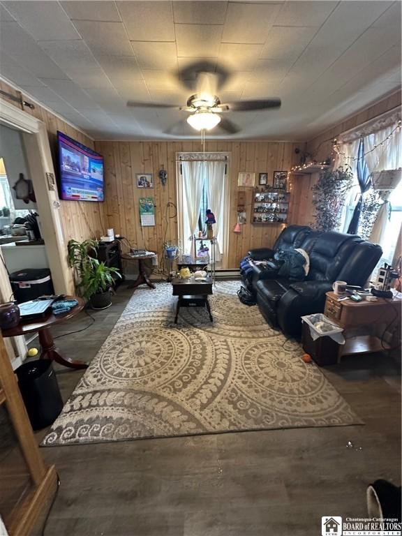 living room with a healthy amount of sunlight, wooden walls, and ceiling fan