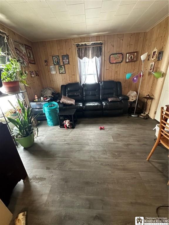 living room with dark hardwood / wood-style floors and wood walls