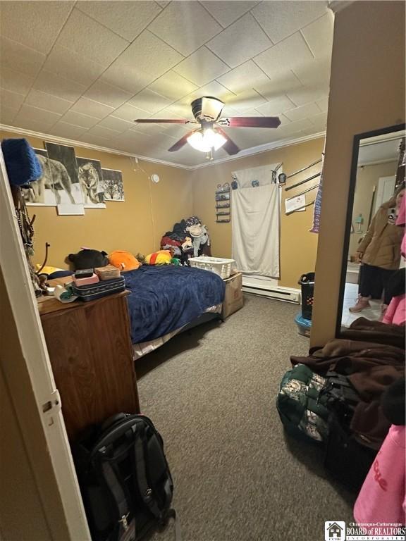 carpeted bedroom featuring ornamental molding, a baseboard heating unit, and ceiling fan