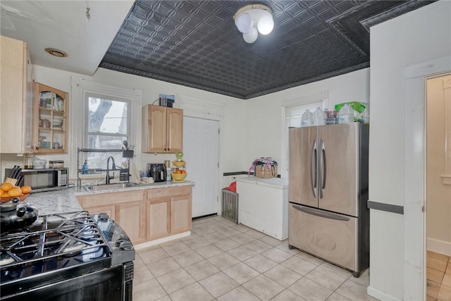 kitchen featuring sink, light tile patterned floors, appliances with stainless steel finishes, light stone countertops, and light brown cabinetry