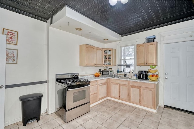 kitchen featuring sink, light brown cabinetry, stainless steel stove, and light tile patterned floors