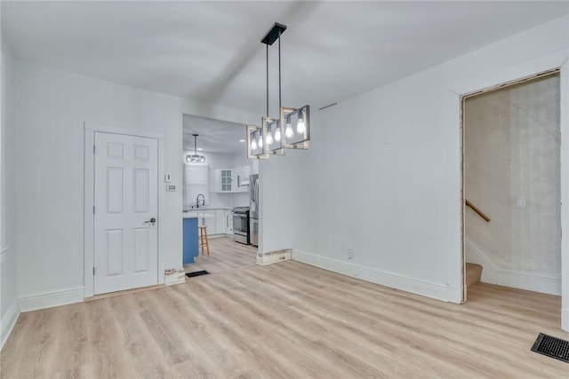 unfurnished dining area with sink and light wood-type flooring