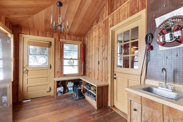 mudroom with sink, dark wood-type flooring, vaulted ceiling, and wood walls