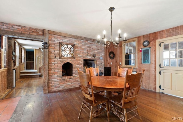 dining room featuring a brick fireplace, a notable chandelier, and hardwood / wood-style flooring