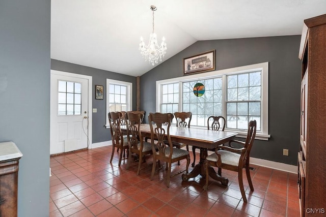 dining space featuring dark tile patterned flooring, baseboards, a notable chandelier, and lofted ceiling
