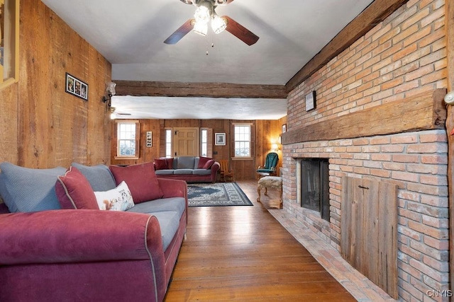 living area with a ceiling fan, wood walls, and hardwood / wood-style floors