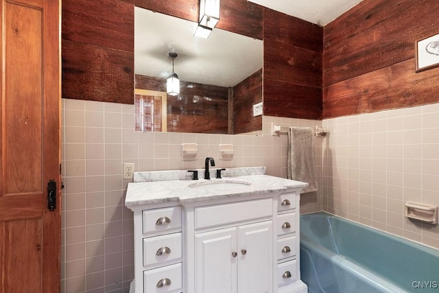full bathroom with vanity, a tub, and tile walls