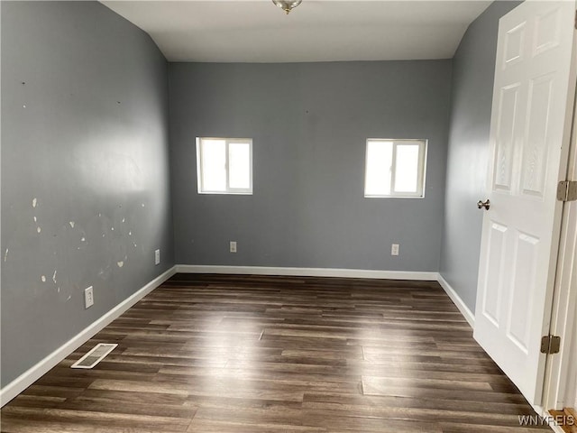 empty room featuring plenty of natural light and dark hardwood / wood-style floors