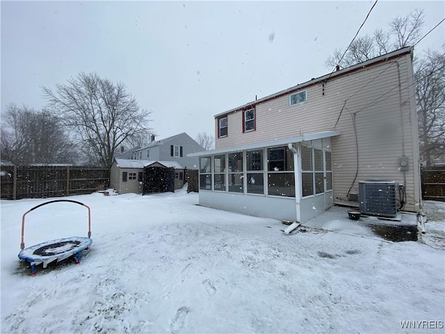 snow covered property featuring a sunroom and central air condition unit