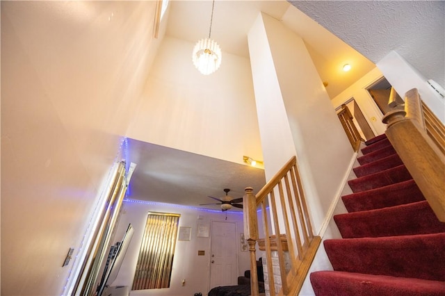 staircase with a notable chandelier, a towering ceiling, and a textured ceiling