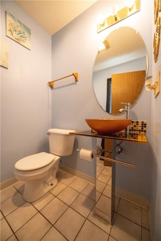 bathroom with tile patterned flooring, sink, a textured ceiling, and toilet