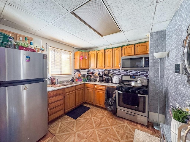 kitchen featuring tasteful backsplash, a paneled ceiling, and stainless steel appliances