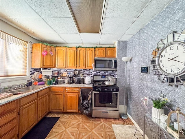 kitchen featuring sink, a paneled ceiling, light parquet floors, and appliances with stainless steel finishes