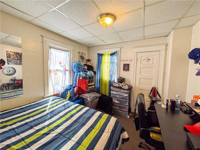 carpeted bedroom featuring a drop ceiling