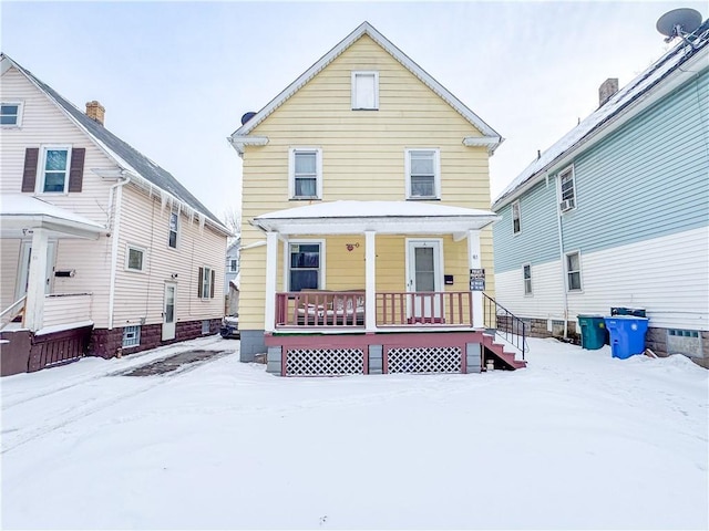 snow covered house featuring covered porch