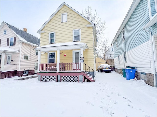 snow covered house featuring a porch