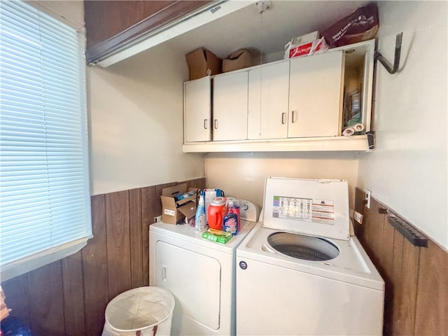 laundry room featuring cabinets, washing machine and clothes dryer, and wooden walls