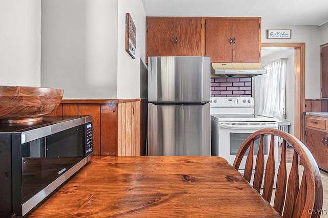 kitchen featuring wooden walls, range hood, and appliances with stainless steel finishes