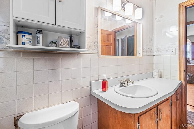 bathroom featuring vanity, tile walls, and toilet