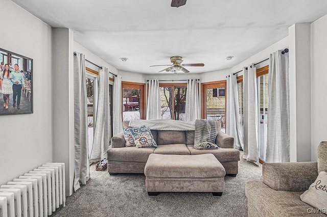 carpeted living room with ceiling fan and radiator heating unit