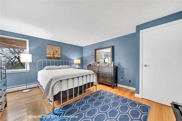 bedroom with wood-type flooring and a baseboard heating unit