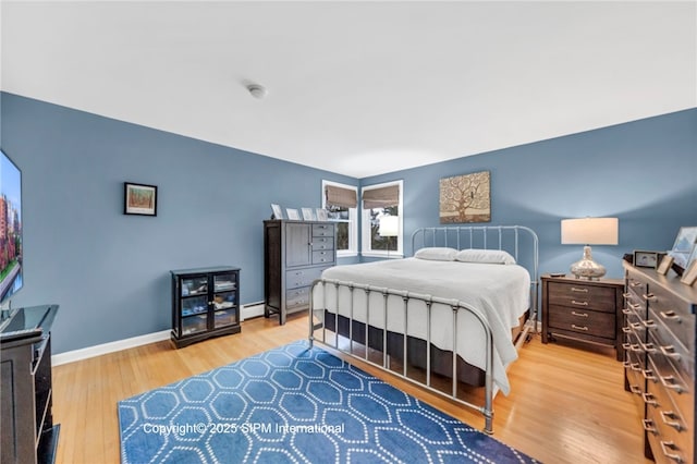 bedroom with a baseboard radiator and light hardwood / wood-style floors