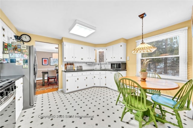 kitchen with pendant lighting, sink, appliances with stainless steel finishes, white cabinetry, and backsplash