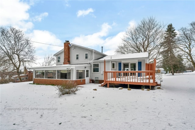 snow covered house with a sunroom and a deck